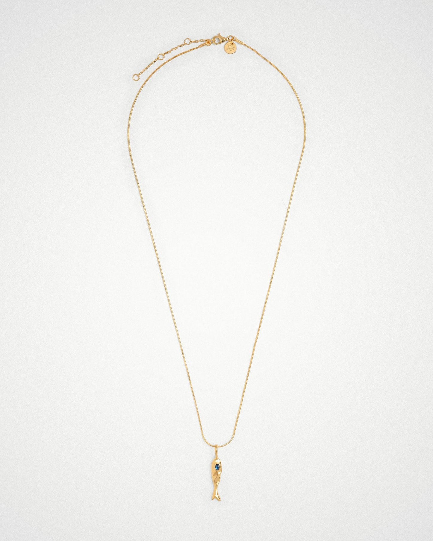 Molten 18k plated and rhodium silver fish-shaped pendant with blue sapphire on a round snake chain necklace.