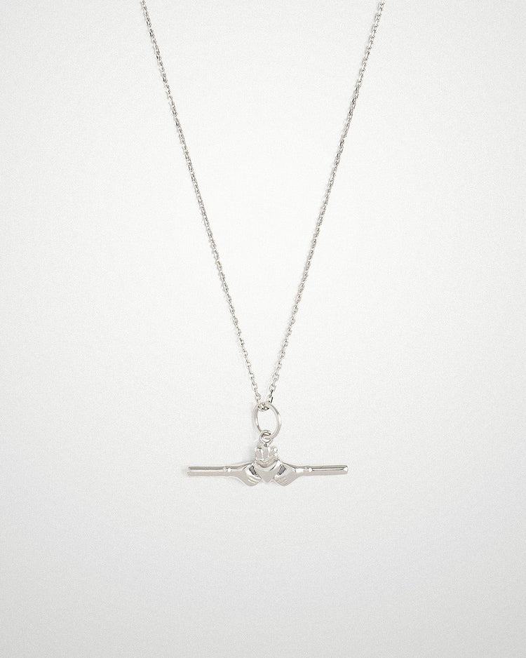Close-up of a delicate 18k gold-plated Claddagh bar necklace being worn, by Lines & Current