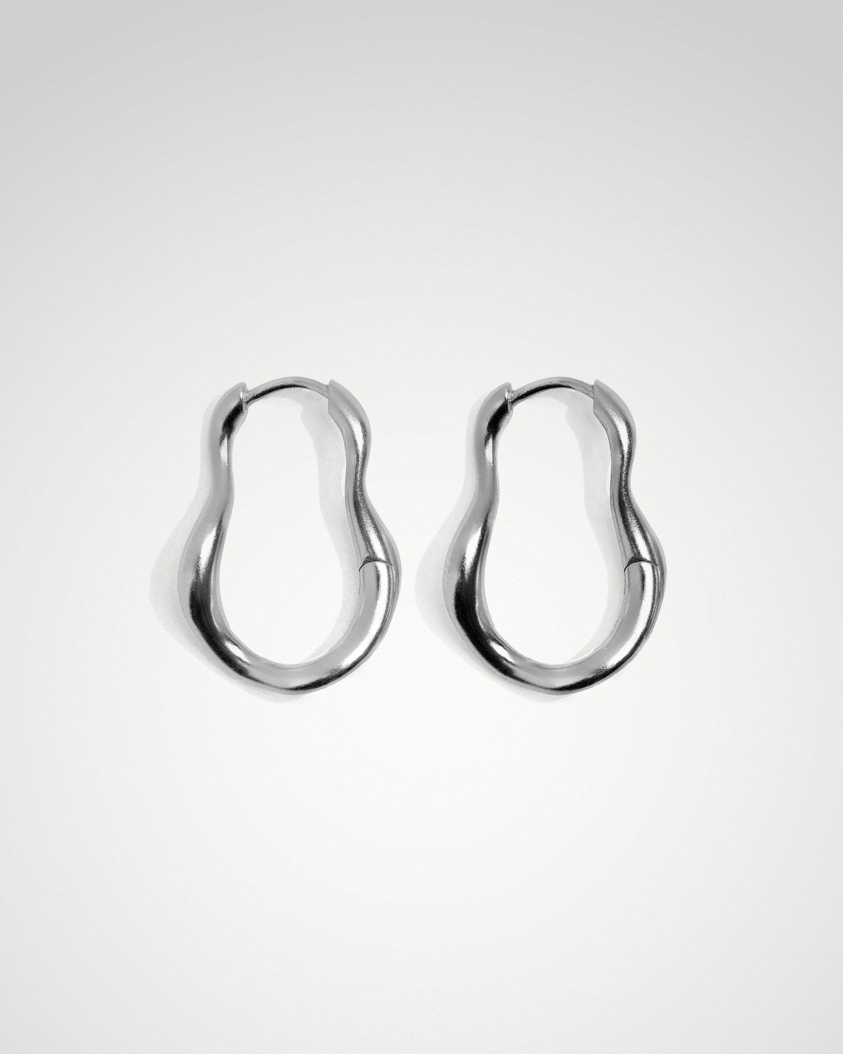 Flo oval hoop earrings with wave detail, 20mm drop, in rhodium plated.