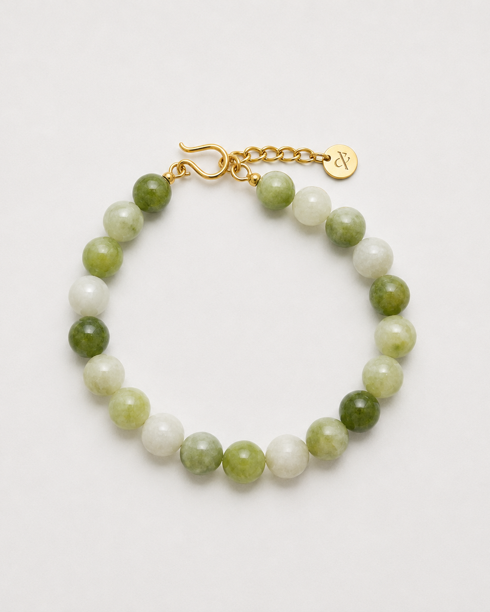 A beaded bracelet made of alternating light green and white marbled beads, finished with a gold clasp and extender chain featuring a small round logo charm, shown on a plain light background.
