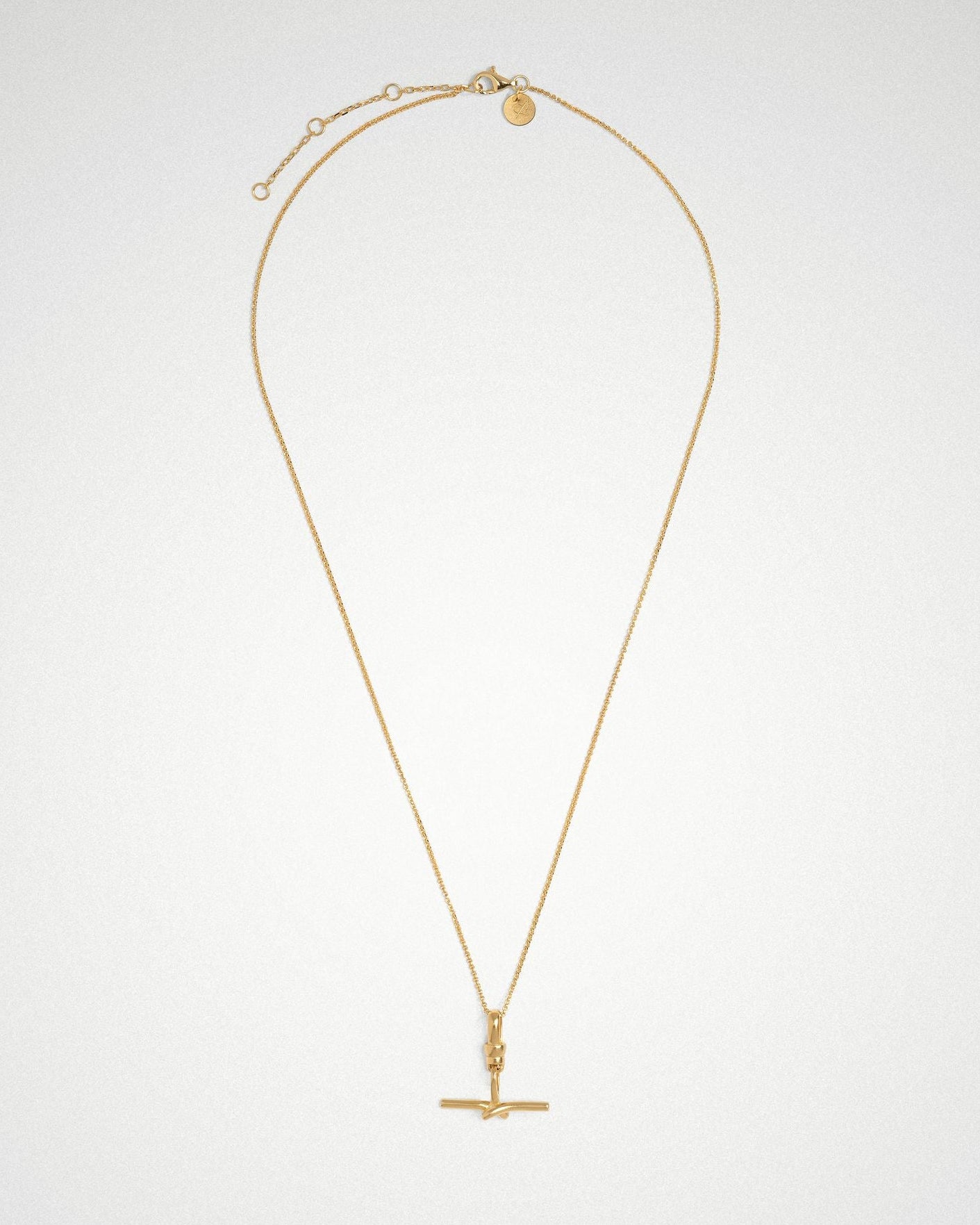 Gold necklace with a Tbar pendant on a light gray background